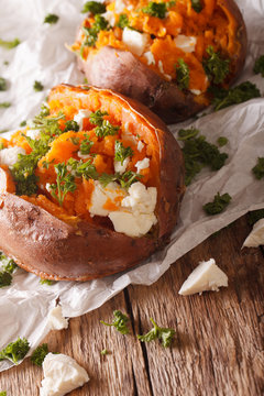 healthy food: baked sweet potato stuffed with cheese and parsley close-up. Vertical