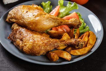 Roasted chicken legs with potato wedges and tomatoes