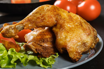 Roasted chicken legs with potato wedges and tomatoes
