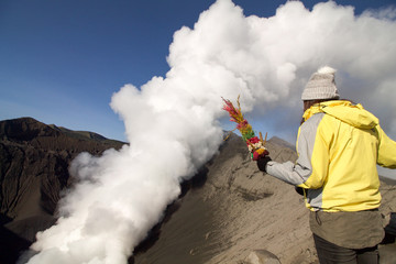 Obraz premium tourist throws flowers in the sacred crater of the Bromo volcan