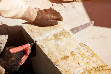 Close-up, builder with a hand saw cuts foam block. Construction works