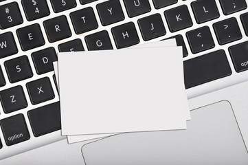 Top view flat lay blank business card on computer keyboard with copy space area