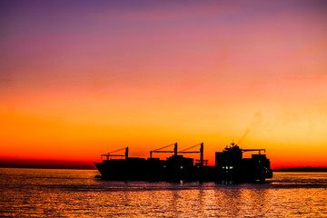 Big cargo ship silhouette leaving harbor.