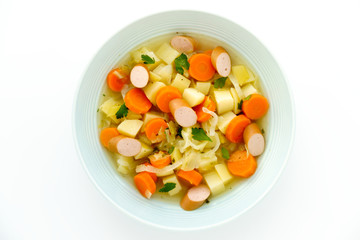 Close-up of a homemade Frankfurter Sausage Stew in a blue soup plate isolated on white background. 