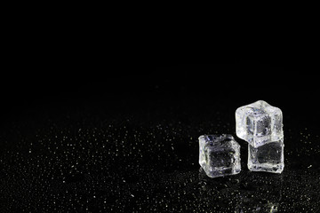 ice cubes reflection on black table background.