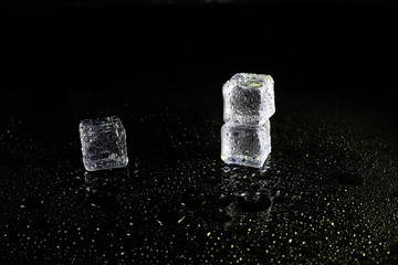 ice cubes reflection on black table background.