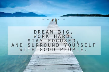 Inspirational motivating quote on long exposure of wooden jetty at sea facing island with cloud and sky at twilight. Dream big, work hard, stay focused, and surround yourself with good people.