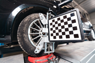 Car on stand with sensors wheels for alignment camber check in workshop of Service station.