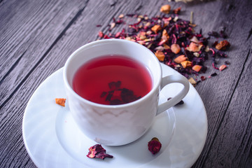 Cup of tea mix of leaves, fruits and dried fruits on rustic back