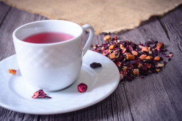 Cup of tea mix of leaves, fruits and dried fruits on rustic back