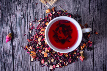 Cup of tea mix of leaves, fruits and dried fruits on rustic back