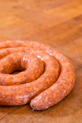 Fototapeta premium Rolled raw red sausage on the table