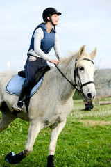 beautiful young woman riding horse and training for jump hurdle equitation competition outdoor