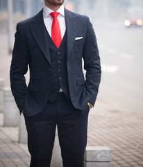 Male model in a black suit with a red tie