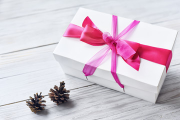 white box with red ribbon on a light wooden background.

