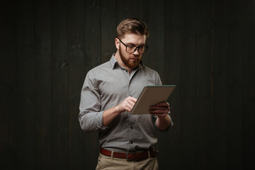 Portrait of a bearded man in eyeglasses using tablet computer