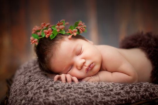 beautiful newborn sleeping baby girl in a wicker basket on a wooden background