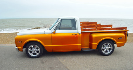  Classic Gold and white pickup truck on seafront promenade with sea in background - obrazy, fototapety, plakaty
