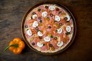 Various ingredients for pizza. Flour, butter, mushrooms, cucumbers, cherry tomatoes, olives,Mozzarella  , sausage, cheese. Dark background.