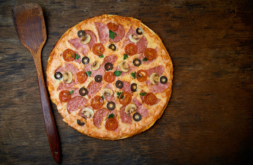 Various ingredients for pizza. Flour, butter, mushrooms, cucumbers, cherry tomatoes, olives,Mozzarella  , sausage, cheese. Dark background.