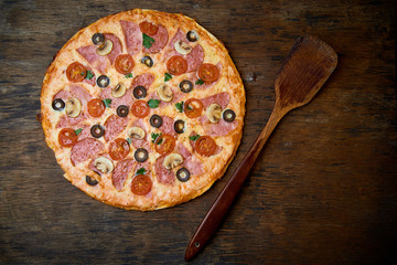 Various ingredients for pizza. Flour, butter, mushrooms, cucumbers, cherry tomatoes, olives,Mozzarella  , sausage, cheese. Dark background.