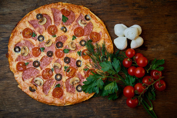 Various ingredients for pizza. Flour, butter, mushrooms, cucumbers, cherry tomatoes, olives,Mozzarella  , sausage, cheese. Dark background.