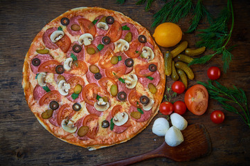 Various ingredients for pizza. Flour, butter, mushrooms, cucumbers, cherry tomatoes, olives,Mozzarella  , sausage, cheese. Dark background.