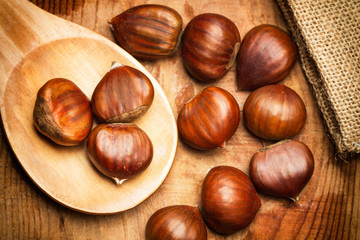 Castañas naturales y crudas sobre una cuchara de madera sobre un fondo rústico de madera. vista superior. Macro