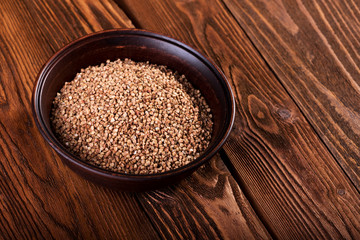 Buckwheat in a ceramic bowl on a wooden background