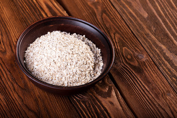 Oat flakes in a ceramic bowl on a wooden background