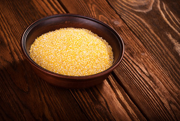 Corn grits in a ceramic bowl on a wooden background