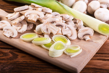 Fresh vegetables, leek and mushrooms, cut into slices on a wooden Board