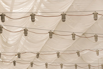 Many gray bulbs hanging under a dome of white cloth, background