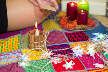 A girl lights a candle near a Christmas tree.