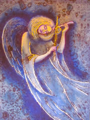 The girl an angel plays a soul melody on a violin. The image of an angel on is violet a blue background