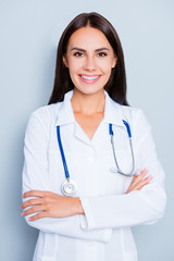 Portrait of pretty female doctor with beaming smile and crossed