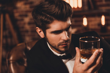Portrait of rich handsome man holding glass of cognac and relaxi