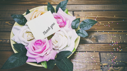 Rose flowers on a plate on a wooden table, a note on the paper