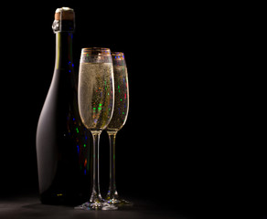 A bottle of champagne and two glasses of champagne on a black background