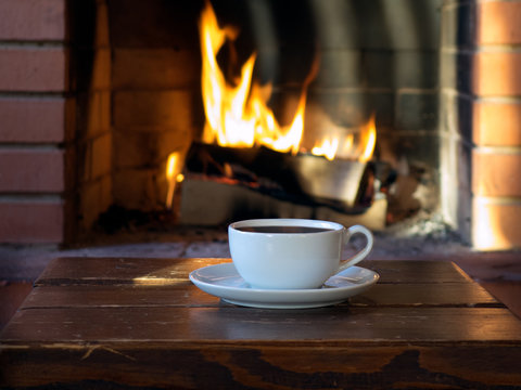 cup of coffee or tea on a background of a burning fire in the fireplace
