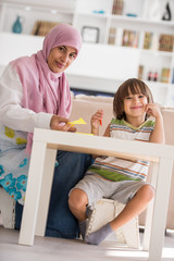 Arabic mother with little son learning in living room