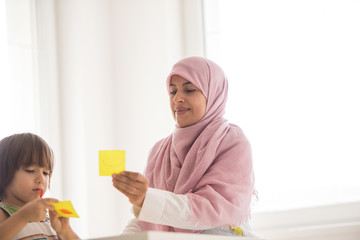 Arabic mother with little son learning in living room