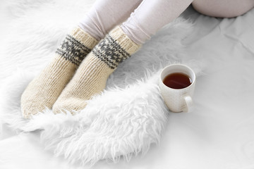 Obraz na płótnie Canvas Female feet in socks with cup of tea on bed