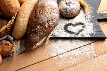 Lots of fresh bread and flour on a board with drawing heart