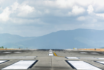 Runway with mountain in the background in cloudy day