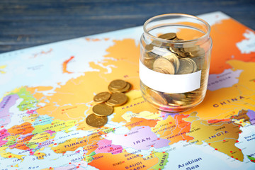 Glass jar with coins on world map