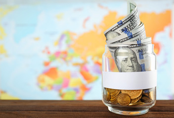Glass jar with money on world map background