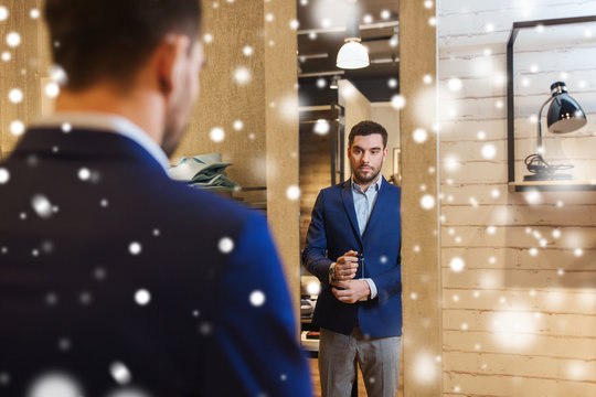 Man Trying Jacket On At Mirror In Clothing Store