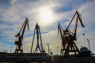 Fototapeta na wymiar Beautiful landscape of cranes in shipyard against a backlight in coast of Huelva, Andalusia, Spain.