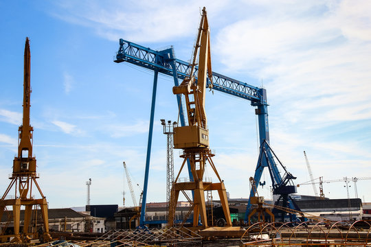 Beautiful landscape of  cranes in shipyard against a backlight in coast of Huelva, Andalusia, Spain.